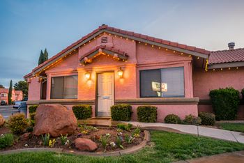 A house with a red roof and a white door is surrounded by a garden.
